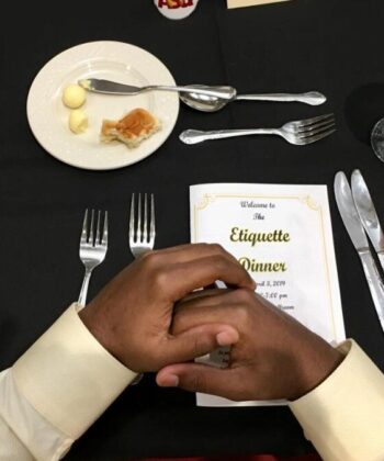 A man extends his hand over a table, showcasing a plate of food in front of him. - Hausion