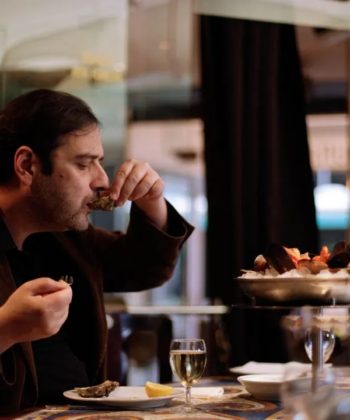 A man enjoying a meal at a restaurant, seated at a table with a plate of food in front of him. - Hausion