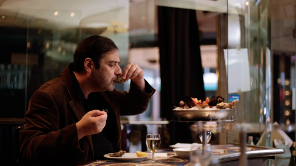 A man enjoying a meal at a restaurant, seated at a table with a plate of food in front of him. - Hausion