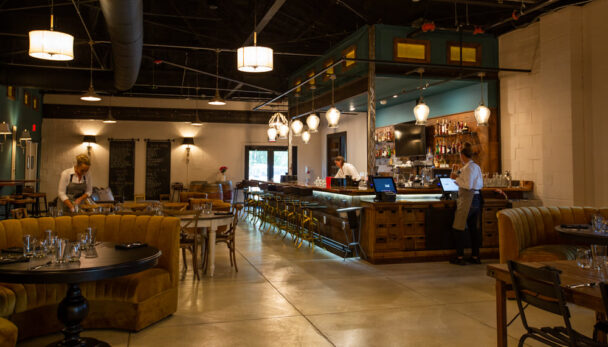 Interior of a restaurant featuring a bar and tables, creating a warm and inviting dining atmosphere. - Hausion