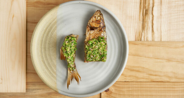 A plate featuring two fish garnished with a vibrant green sauce, elegantly presented for a delightful dining experience. - Hausion