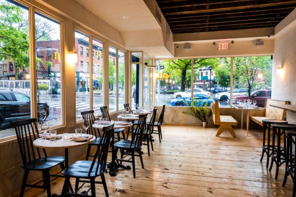 A cozy restaurant interior featuring neatly arranged tables and chairs for dining. - Hausion