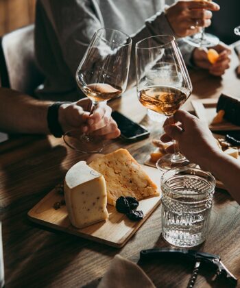 A group of people joyfully toasting with wine glasses around a beautifully set dining table. - Hausion