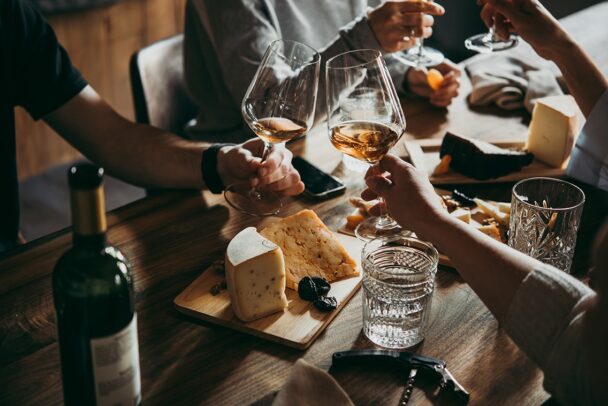 A group of people joyfully toasting with wine glasses around a beautifully set dining table. - Hausion