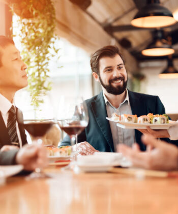 Businessmen engaged in conversation while dining together at a restaurant, showcasing a professional networking atmosphere. - Hausion