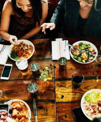 A diverse group of individuals enjoying a meal together at a table filled with various dishes. - Hausion