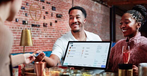 A man and woman smile together while holding a laptop, showcasing a moment of collaboration and joy. - Hausion