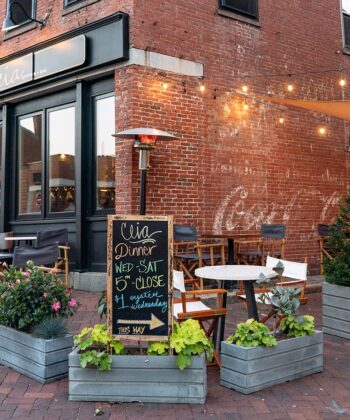 A brick building featuring outdoor tables and chairs, inviting patrons to enjoy the fresh air and ambiance. - Hausion