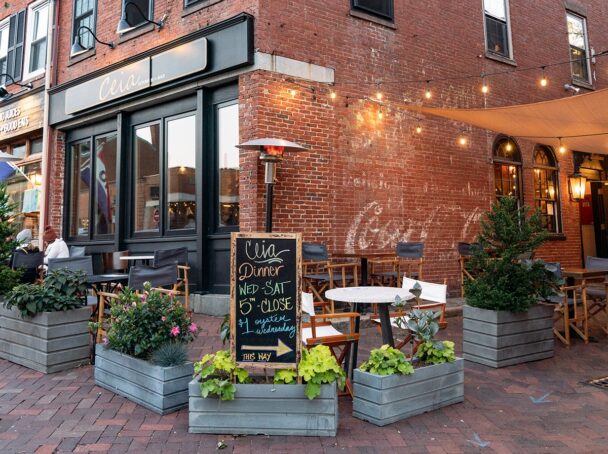 A brick building featuring outdoor tables and chairs, inviting patrons to enjoy the fresh air and ambiance. - Hausion