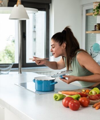 A woman enjoys a bowl of food while seated in her kitchen, surrounded by a warm and inviting atmosphere. - Hausion