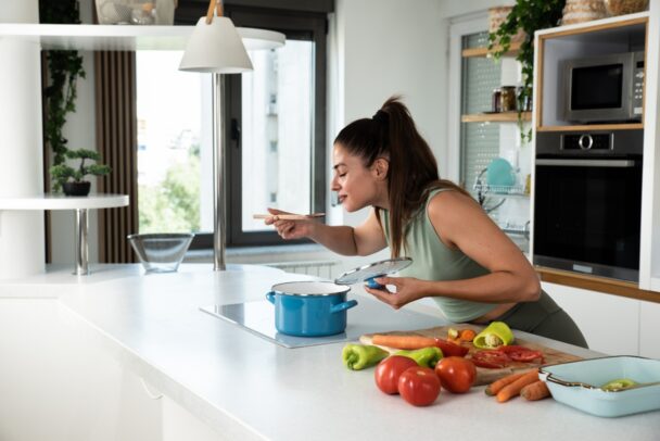 A woman enjoys a bowl of food while seated in her kitchen, surrounded by a warm and inviting atmosphere. - Hausion