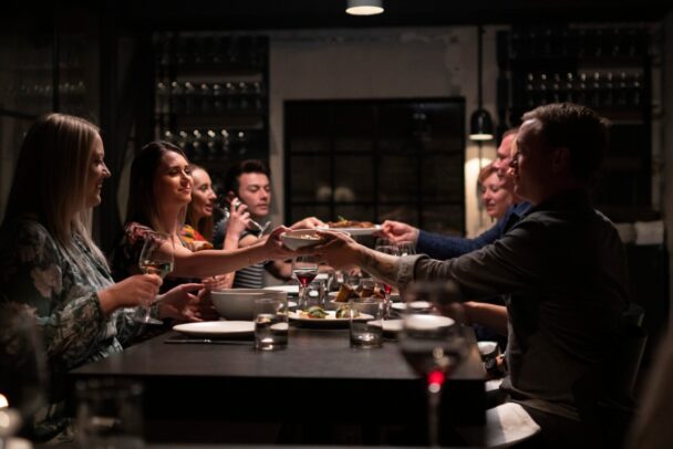 Friends joyfully toasting with drinks at a restaurant, capturing a moment of celebration and camaraderie. - Hausion