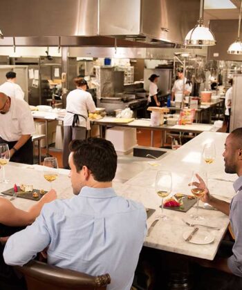 A lively group of friends enjoying a meal together at a restaurant table, sharing laughter and good food. - Hausion