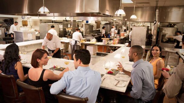 A lively group of friends enjoying a meal together at a restaurant table, sharing laughter and good food. - Hausion