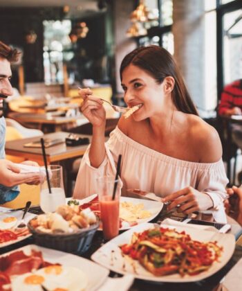 A cheerful group of friends enjoying a delicious breakfast together at a cozy restaurant, sharing laughter and good food. - Hausion